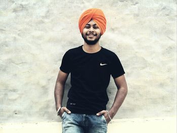 Portrait of young man standing against wall