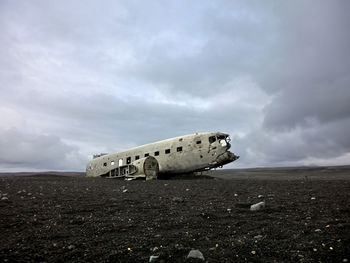 Abandoned airplane on sand against sky