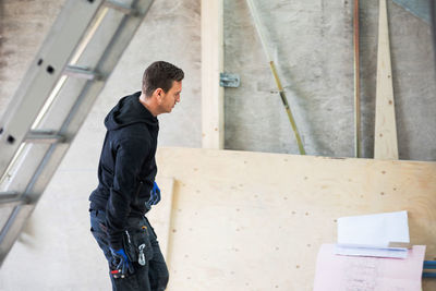 Concentrated manual worker looking at blue prints in construction site