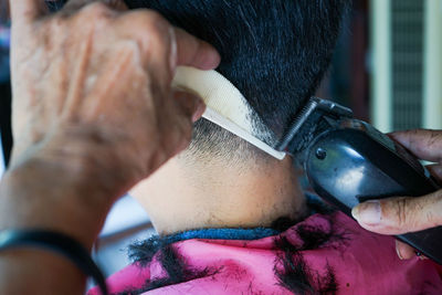 Closeup rear view head of man having a hair cut with battalion and comb