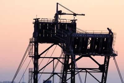 Low angle view of silhouette cranes against clear sky