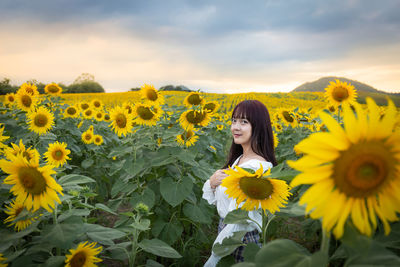 Woman standing on sunflower field