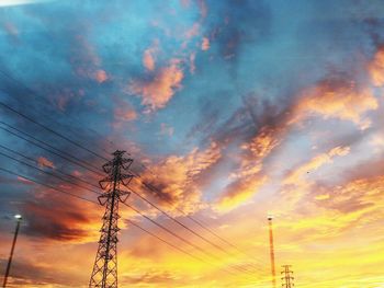 Low angle view of silhouette electricity pylon against sky