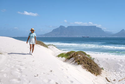 Woman walking on beach against sky