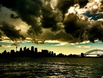 Silhouette of buildings against cloudy sky at sunset