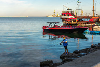 Man on rock in sea against sky