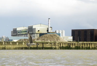 Factory by sea against sky in city