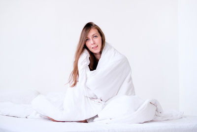 Portrait of young woman sitting on bed