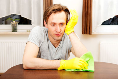 Young man cleaning table at home