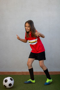 Portrait of smiling girl playing soccer against wall