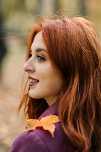 Mental health in autumn. happy red-haired woman holding yellow maple autumn leaves