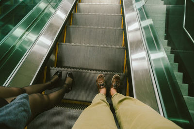 Low section of women standing on escalator