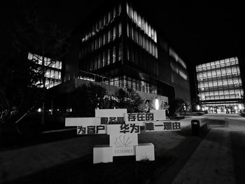 Text on illuminated street against buildings at night