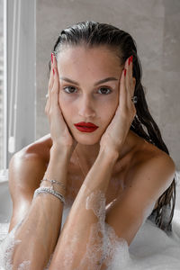 Portrait of woman wearing red lipstick relaxing in bath