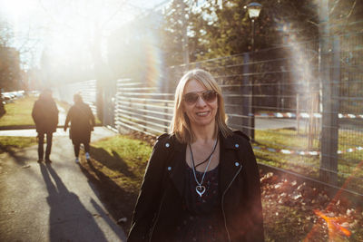 Portrait of smiling woman wearing sunglasses standing in park
