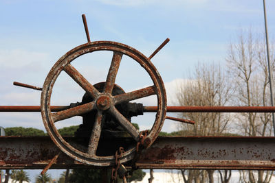 Close-up of rusty wheel against sky