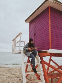 Full length of woman sitting on beach against sky