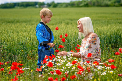 Mother with son by red flowers on land