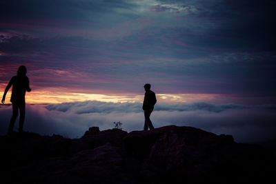 Silhouette man standing on rock against sky during sunset