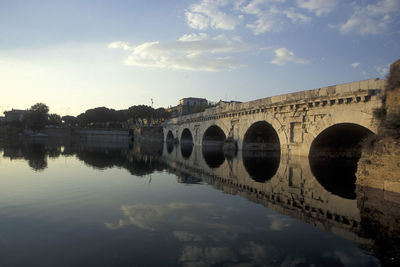 Arch bridge over river against sky