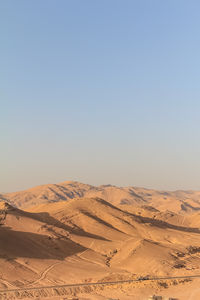 A wide and arid desert landscape showcasing rugged terrain and a hazy mountain horizon. 