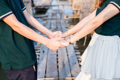 Midsection of couple holding hands on pier