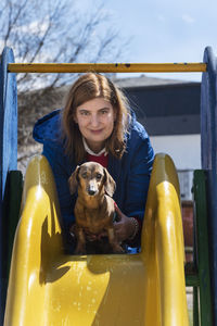 Portrait of woman with dog playing on slide