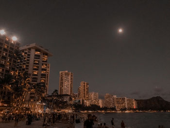 Illuminated city buildings against sky at night