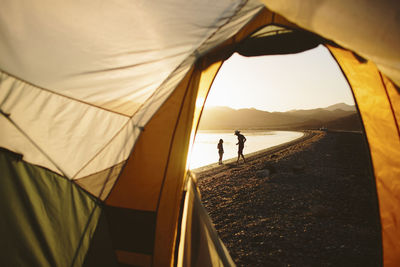 Friends at lakeshore seen through tent