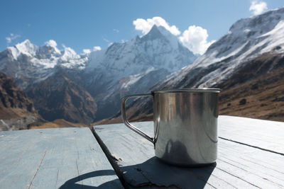 Close-up of mug on table against snowcapped mountains