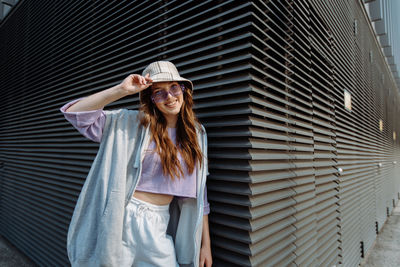 Portrait of young woman standing against wall