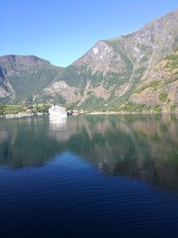 Scenic view of lake and mountains against clear blue sky