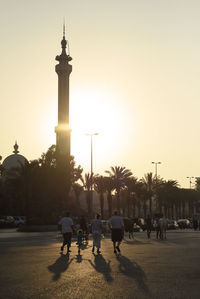 Silhouette people on street in city at sunset