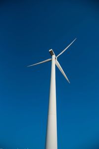 Low angle view of windmill against clear blue sky