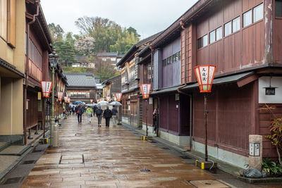 People walking on street amidst buildings during rainy season