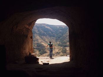 Rear view of teenage boy standing against mountain seen through archway