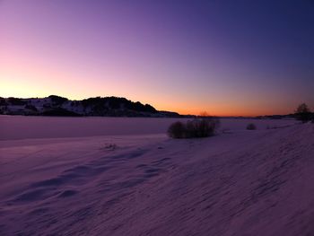 Scenic view of snow covered field against sky during sunset