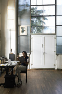 Female designer examining document while sitting at home office