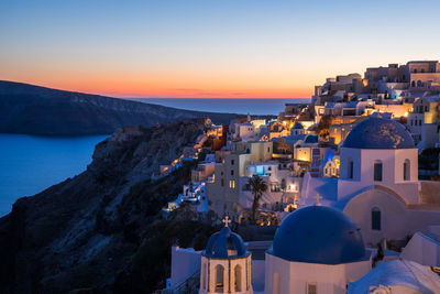 Townscape by sea against sky during sunset