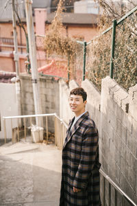 Portrait of young man standing against building