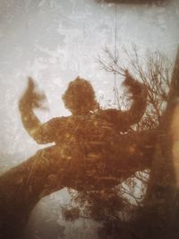 Double exposure of man touching tree against sky