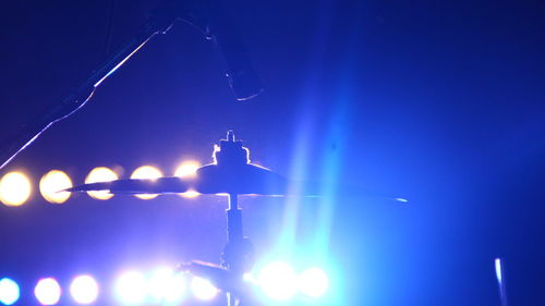 Low angle view of illuminated lighting equipment against blue sky