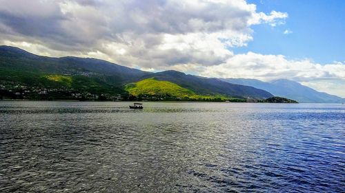 Scenic view of lake by mountains against sky