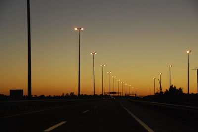 Cars on street against sky during sunset