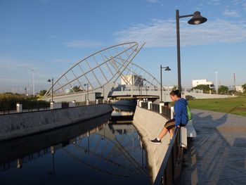 Man on bridge over river against sky