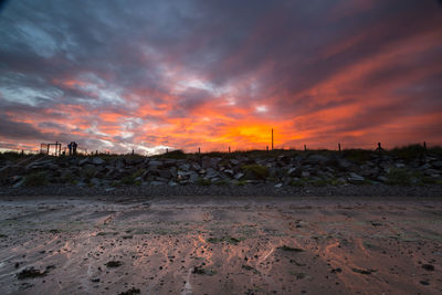 Scenic view of landscape against cloudy sky at sunset