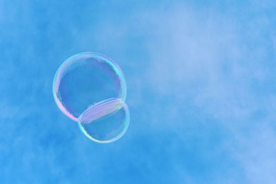 Low angle view of bubbles against blue sky