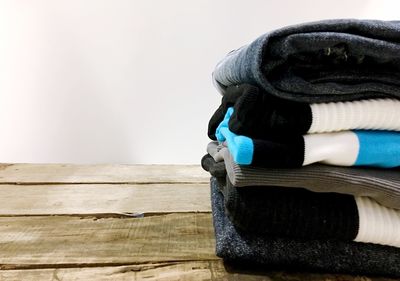 Stack of folded laundry on wooden table against white background