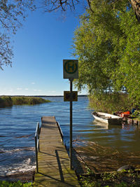 Sign board by jetty at lakeshore