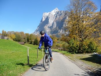 Teenage boy riding bicycle on road against mountains